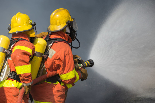 fire-fighting-course-2-firefighters-spraying-water-in-fire-fighting-with-dark-smoke-b-78900888