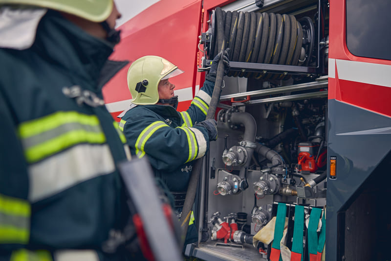 fire-fighting-course-fireman-wearing-safe-helmet-standing-next-to-the-fire-engine