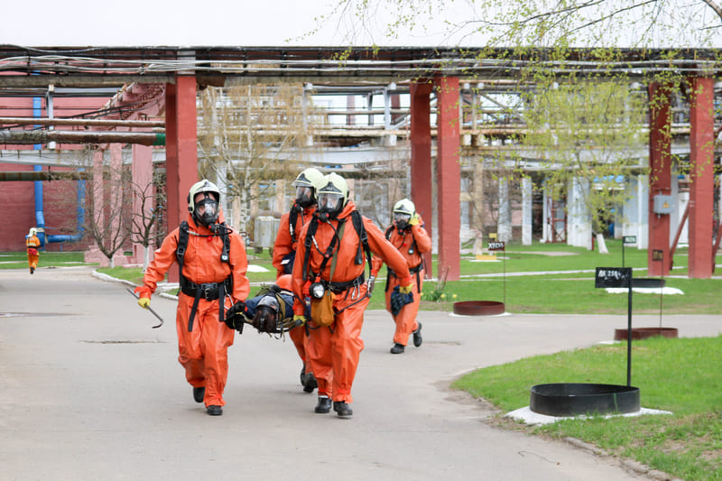 fire-fighting-training-rescuers-in-orange-protective-fire-resistant-suits-white-helmets-and-gas-masks-bear-the-injured-pe