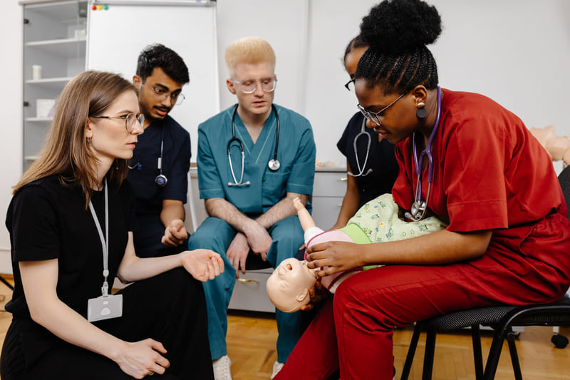 first-aid-training-diverse-group-of-medical-students-learning-infant-care-on-a-medical-manikin-during-a-training-session