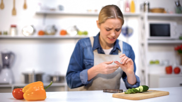 health-and-safety-course-female-cut-finger-while-slicing-cucumber-accident-in-kitchen-household-injury-151821144