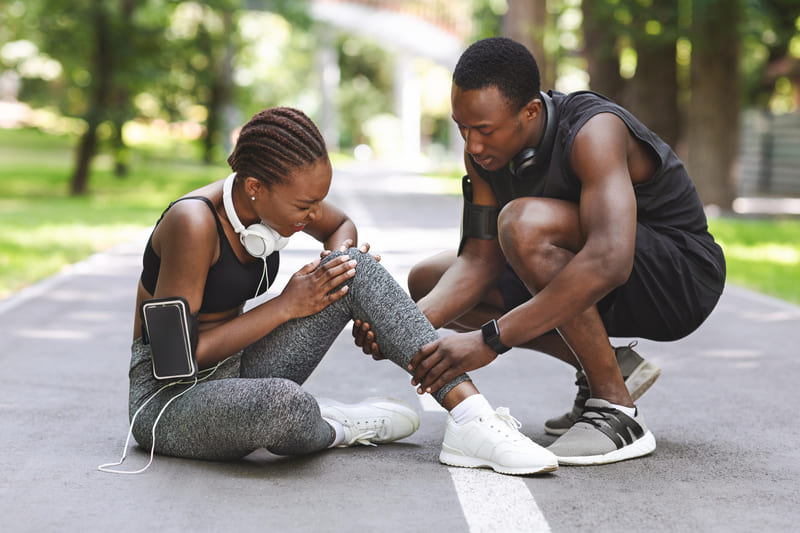 first-aid-course-sport-injury-woman-suffering-from-knee-trauma-while-jogging-with-boyfriend-outdoors